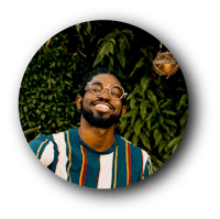 a man with glasses smiling in front of plants